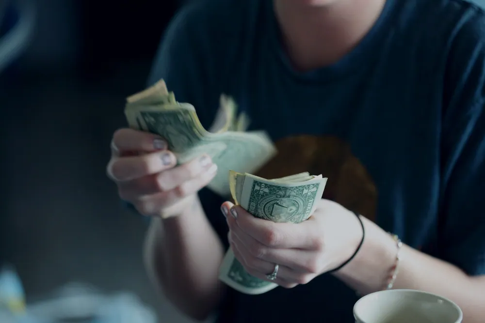 En tjugofyraårig kvinna som räknar dollarsedlar.
