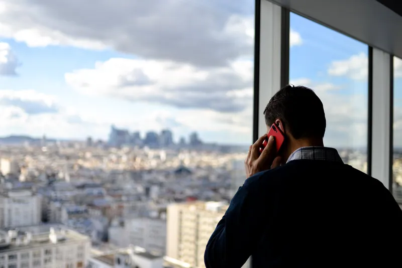 man die telefoneert terwijl hij uit het raam kijkt